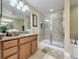 Bathroom featuring a walk-in shower, double sinks with granite countertops, and modern lighting at 802 Suffolk Pl, Davenport, FL 33896