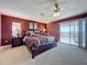 Spacious main bedroom featuring a king bed, sliding glass doors to balcony, ceiling fan, and ensuite bathroom at 802 Suffolk Pl, Davenport, FL 33896