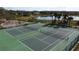 Overhead view of two well-maintained tennis courts with a playground and pretty pond in the background at 802 Suffolk Pl, Davenport, FL 33896
