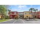 Colorful townhome exterior featuring well-manicured landscaping, a parking lot, and a vibrant facade at 8517 Crystal Cove Loop, Kissimmee, FL 34747