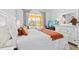 Bright bedroom featuring a white bed with an orange throw, two nightstands, a dresser and a window at 917 Orange Cosmos Blvd, Davenport, FL 33837