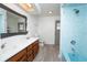Bright bathroom with blue-tiled shower, wood cabinets and double sinks at 9916 Jackson Rd, Leesburg, FL 34788