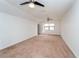 Bright bedroom featuring neutral carpeting, a ceiling fan, and a large window for natural light at 9916 Jackson Rd, Leesburg, FL 34788