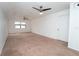 Bright bedroom featuring neutral carpeting, a ceiling fan, and a large window for natural light at 9916 Jackson Rd, Leesburg, FL 34788