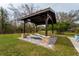 Relaxing backyard gazebo featuring two lounge chairs, stone pillars, and a charming view of the lawn at 9916 Jackson Rd, Leesburg, FL 34788