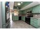 Kitchen with light green cabinets, stainless steel appliances and wood-look floors at 9916 Jackson Rd, Leesburg, FL 34788