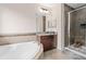 Bathroom featuring a soaking tub, glass-enclosed shower, warm wood cabinets, and modern fixtures at 13831 Briand Ave, Orlando, FL 32827