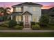 Charming two-story home with landscaped yard, colorful pink entry door, and covered porch at 13831 Briand Ave, Orlando, FL 32827