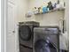 Modern laundry room featuring a front-load washer and dryer set, storage shelves, and a convenient layout at 1502 Fern Bay Ct, Orlando, FL 32824