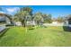Lush green backyard featuring a swing set, slide, and ample space for outdoor recreation and Gathering fun at 1518 Mississippi Ave, St Cloud, FL 34769
