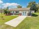 Lovely single-story home featuring a lush green lawn, concrete driveway, and inviting double doors, perfect for comfortable living at 1518 Mississippi Ave, St Cloud, FL 34769