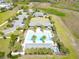 Aerial view of a community pool featuring palm trees, lounge chairs, and nearby recreation facilities at 1723 Lake Sims Pkwy, Ocoee, FL 34761