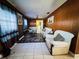 Inviting living room featuring tiled floors, paneled walls, and comfortable white couches at 205 Elinor S Ave, Dundee, FL 33838