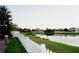 Backyard features a white picket fence, lush green grass, and a serene lake view, providing a peaceful outdoor space at 2224 Paria Ln, Kissimmee, FL 34758