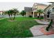 View of the front yard showing the driveway and lush grass, as well as palm trees and landscaping details at 2224 Paria Ln, Kissimmee, FL 34758