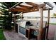 Outdoor kitchen has a stainless steel grill and stone backsplash, plus sink and prep area, for outdoor dining at 2224 Paria Ln, Kissimmee, FL 34758