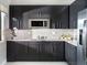 Modern kitchen with sleek black cabinetry, stainless steel appliances, and a stylish backsplash at 231 Villa Domani Cir # 59, Davenport, FL 33896