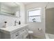 Bright bathroom with white vanity, decorative mirror, and a shower with gray tile at 3030 Little Sound Dr, Orlando, FL 32827