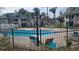 Community pool area surrounded by black metal fence, lounge chairs, and lush greenery at 6148 Westgate Dr # 302, Orlando, FL 32835