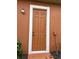 Exterior shot of a home's side entry door framed with a white border and a small shrub at 619 Tapatio Ln, Kissimmee, FL 34759