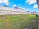Flat backyard area with green grass and a retaining wall with a white fence at 709 Blackstone St, Minneola, FL 34715
