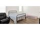 Bedroom with wood-look floors, black metal frame bed, black chair, and neutral walls at 709 Blackstone St, Minneola, FL 34715