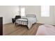 Bright bedroom features wood-look floors, two windows, black metal bed frame, and a leather chair at 709 Blackstone St, Minneola, FL 34715