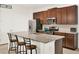 Kitchen features stone countertops, wood cabinets, stainless steel appliances, and barstool seating at 709 Blackstone St, Minneola, FL 34715