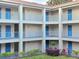 Exterior of a condo building with blue doors, matching blue metal railing, and well maintained lawn and landscaping at 7240 Westpointe Blvd # 1122, Orlando, FL 32835