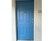 Close up of the blue entry door with door knocker and a unit number plaque reading 