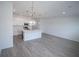 Open-concept kitchen with white cabinets, stainless steel appliances, island, and stylish lighting at 947 Conch Rd, Davenport, FL 33896