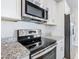 Close-up of a kitchen featuring granite countertops, stainless steel appliances, white cabinets, and wood-style flooring at 152 Big Black Dr, Kissimmee, FL 34759