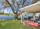 Serene backyard featuring a covered patio, lush lawn, mature tree, and a tranquil water view at 13223 Meadowlark Ln, Orlando, FL 32828