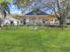 Beautiful backyard with a large tree, a covered patio, lush green lawn, and a black fence at 13223 Meadowlark Ln, Orlando, FL 32828