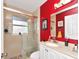 Bathroom featuring a large mirror, glass-enclosed shower, and bright red accent wall at 13223 Meadowlark Ln, Orlando, FL 32828