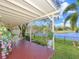 Inviting covered patio with a charming seating area, brick flooring, and views of the serene lake at 13223 Meadowlark Ln, Orlando, FL 32828