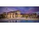 Luxurious clubhouse at dusk with a stunning pool view, elegant architecture, and manicured landscaping at 1432 Rolling Fairway Dr, Davenport, FL 33896