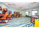 A vibrant game room with an assortment of arcade games and a colorful blue and yellow wavy carpet at 1432 Rolling Fairway Dr, Davenport, FL 33896