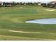 View of golf course with green grass, sand traps, a flag and a pond in a nice community at 1432 Rolling Fairway Dr, Davenport, FL 33896
