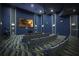 Home movie theater with tiered seating, large screen, and stylish blue decor for immersive entertainment at 1432 Rolling Fairway Dr, Davenport, FL 33896
