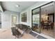Covered outdoor patio featuring a dark picnic table, brick flooring, and sliding glass doors leading to the interior dining area at 1432 Rolling Fairway Dr, Davenport, FL 33896