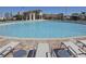 Large community pool with clear blue water, lounge chairs, and umbrellas for relaxation under the sun at 1432 Rolling Fairway Dr, Davenport, FL 33896