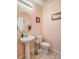 Charming half bathroom featuring a pedestal sink, decorative mirror and subtle pink walls at 1459 Rylee Rock Way, Kissimmee, FL 34744