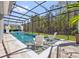 Inviting screened-in pool with wading chairs, adjacent spa, and lush green surroundings at 3010 Camden Way, Davenport, FL 33837