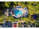 Aerial view showcasing a community pool with lounge chairs, umbrellas, palm trees, parking lot, and nearby townhomes at 4002 San Gallo Dr # 106, Kissimmee, FL 34741
