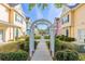 Charming view through a white arbor of colorful townhomes with manicured landscaping at 4002 San Gallo Dr # 106, Kissimmee, FL 34741