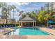Community swimming pool with lounge chairs and a covered pavilion, surrounded by lush landscaping and palm trees at 4002 San Gallo Dr # 106, Kissimmee, FL 34741