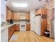 Well-lit kitchen featuring wood floors, wooden cabinets, and white appliances at 439 Madera Pass, Poinciana, FL 34759