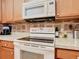 Close-up of kitchen with white appliances, wooden cabinets, and modern countertops at 439 Madera Pass, Poinciana, FL 34759