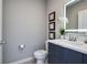 Stylish half-bathroom featuring a modern vanity, illuminated mirror, and decorative wall art at 4417 Le Reve Ct, Kissimmee, FL 34746